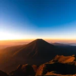 Climber ascending Mount Rinjani’s rugged trail, highlighting the volcanic landscape and lush forests, showcasing adventure and natural beauty of Mt. Rinjani in Indonesia.